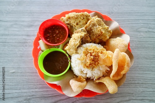 Ayam penyet is Indonesia cuisine smashed fried chicken dish with floss sambal slices of cucumbers fried tofu and tempeh
 photo