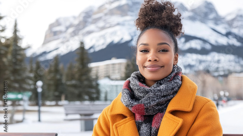 African woman wearing a coat sitting on a bench enjoying the view of the Canadian Rockies