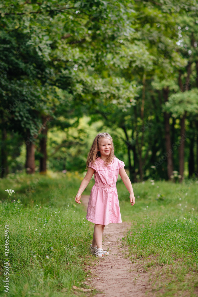 A joyful little girl in a dress jumping with excitement and having fun in a green park on a sunny day A joyful little girl in a dress jumping with excitement and having fun in a green park on a sunny day
