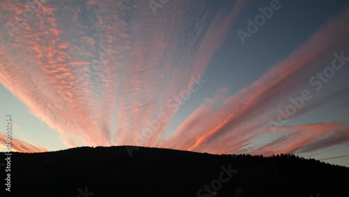 Sonnenuntergang mit Wolkenformationen über einer Bergkette photo