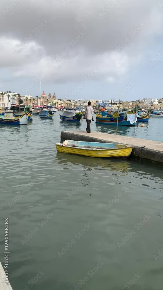 Young woman walking on the pier in Marsaxlokk fishing village, Malta Young woman walking on the pier in Marsaxlokk fishing village, Malta