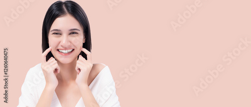 Cheerful young woman with bright smile pointing to cheeks, expressing happiness and confidence. Happy girl get Thooth Whitening  Beautiful woman has beautiful tooth, white teeth, nice tooth alignment.