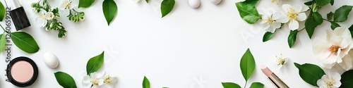 Flat lay of beauty products, flowers, and leaves on a white surface