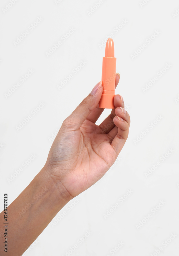 Hand holding pink peach colored lip balm tube object isolated on vertical white background. Hand holding pink peach colored lip balm tube object isolated on vertical white background.