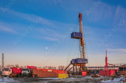 Industrial winter landscape featuring an operational drilling rig with support facilities at a remote worksite during daylight hours