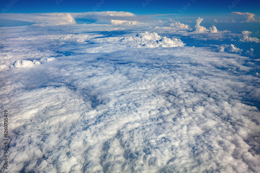 Vast cloudscape stretches across the horizon under a brilliant blue sky