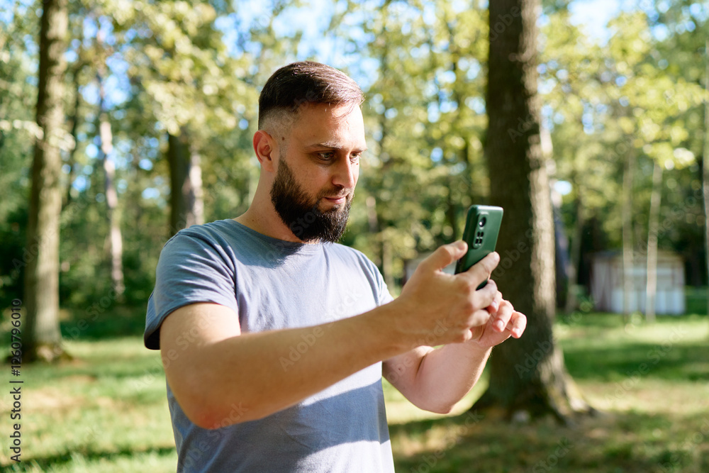 Man Taking Photos Outdoors Using Smartphone in a Scenic Forest Background.. Man Taking Photos Outdoors Using Smartphone in a Scenic Forest Background..