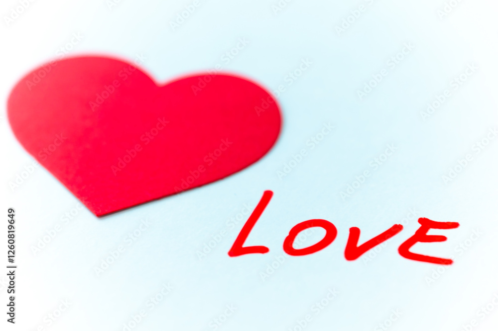 Word Love, handwritten in red, next to red hearts, on a white surface.