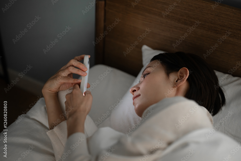Fototapeta premium ベッドでスマホを使う女性