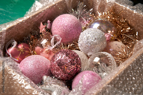 Large cardboard box with pink Christmas balls and Christmas decorations.
