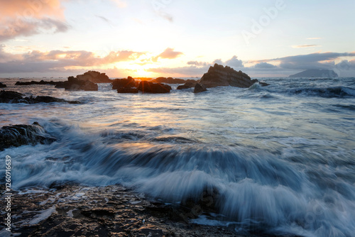 Golden rays of the rising sun light up the rocky beach at Wai'ao, Yilan, Taiwan (Long Exposure Effect)~ Scenery of a beautiful beach illuminated by the first rays of morning sunshine at Ilan, Taiwan  