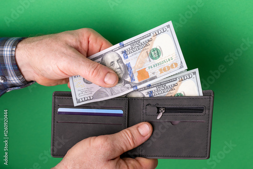 Fototapeta Naklejka Na Ścianę i Meble -  Paying for something with cash money. Hands of a man taking one hundred US dollar banknote and giving it to somebody