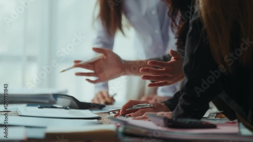 Professional women reviewing financial reports, collaborating over spreadsheets and calculating business metrics near office window