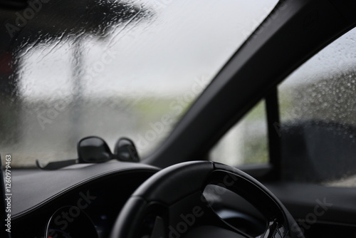 inside of car on a rainy day with steering wheel and dashboard