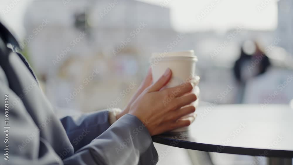 Close-up of a businesswoman's hands holding a coffee cup on a table outdoors, highlighting a moment of relaxation in an urban environment. Business Woman Enjoying Coffee Outdoors in Urban Setting Close-up of a businesswoman's hands holding a coffee cup on a table outdoors, highlighting a moment of relaxation in an urban environment. Business Woman Enjoying Coffee Outdoors in Urban Setting
