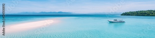 drone shot of yacht anchored near sandbar surrounded by shallow crystal-clear waters and distant mountains photo