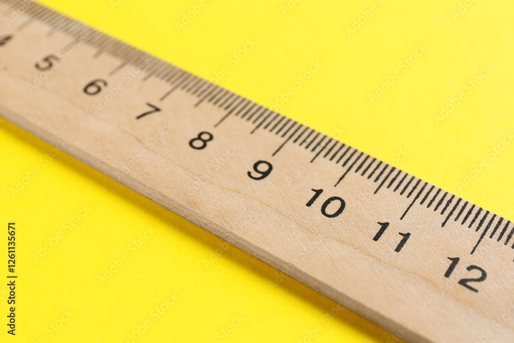 One wooden ruler on yellow background, closeup One wooden ruler on yellow background, closeup