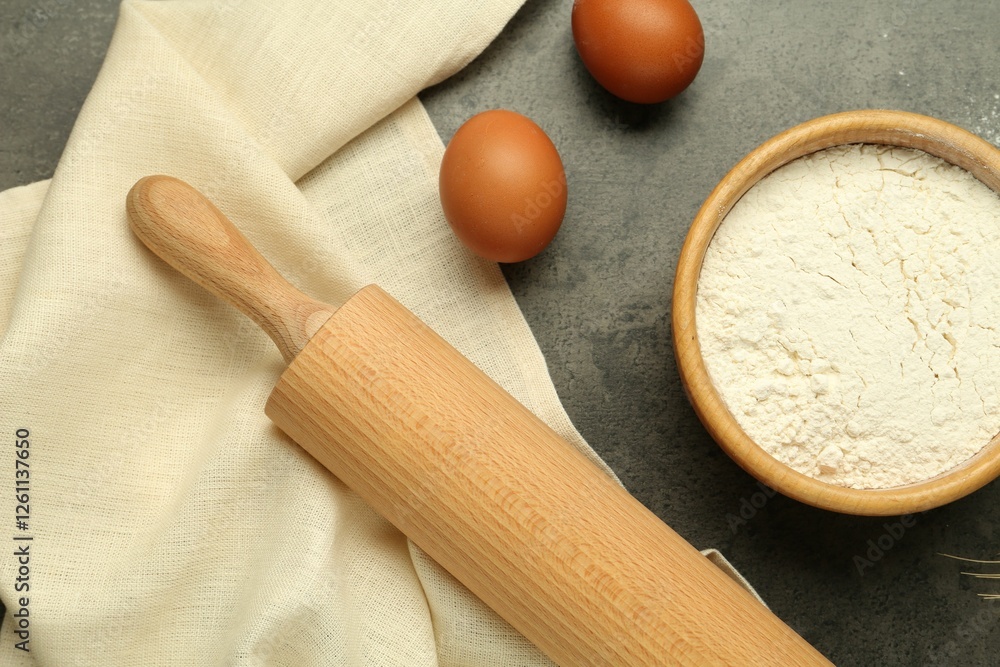 Rolling pin, bowl of flour and eggs on grey table, flat lay Rolling pin, bowl of flour and eggs on grey table, flat lay