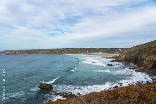 Sous un ciel bleu légèrement voilé, la baie des Trépassés s’étend avec ses eaux bleu profond. Les vagues déroulent leur écume jusqu’au rivage, tandis que la plage apparaît entre les falaises et les ro photo