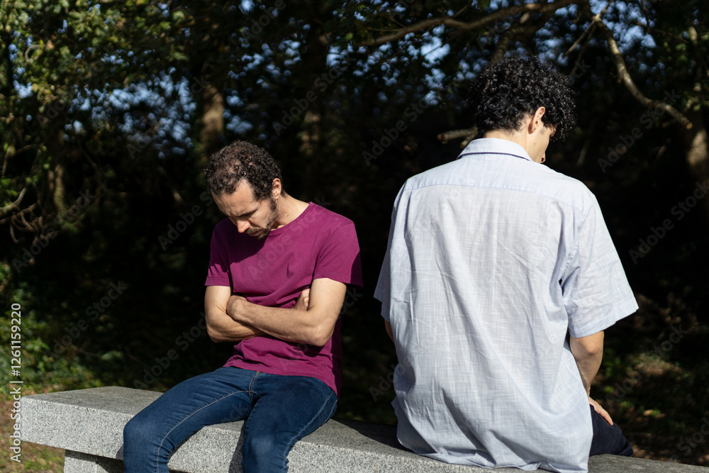 Obraz premium Gay couple arguing and feeling frustrated while sitting on a bench in a park