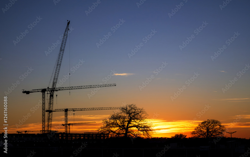 Silhouettes of construction cranes against the evening sky with sunset. Copy space. Silhouettes of construction cranes against the evening sky with sunset. Copy space.