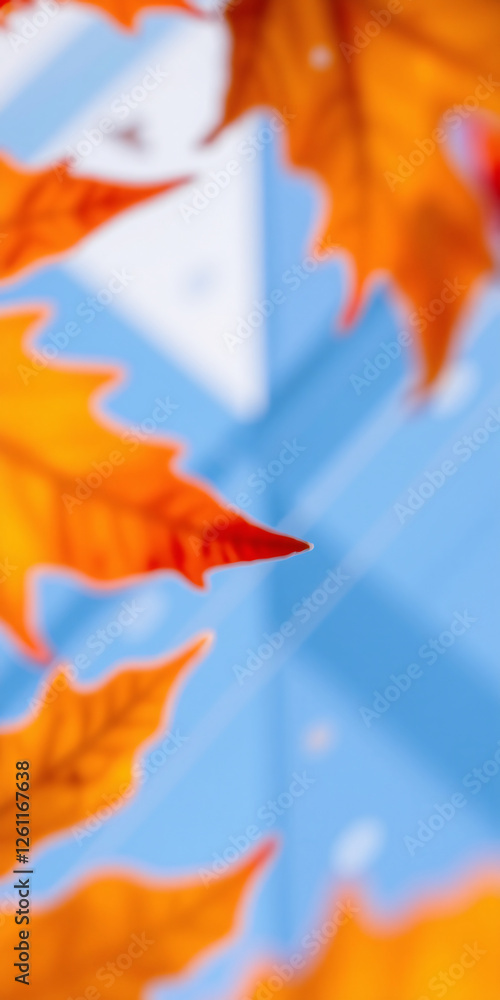 Obraz premium Blurred autumn maple leaves with vibrant orange tones against a modern glass building background