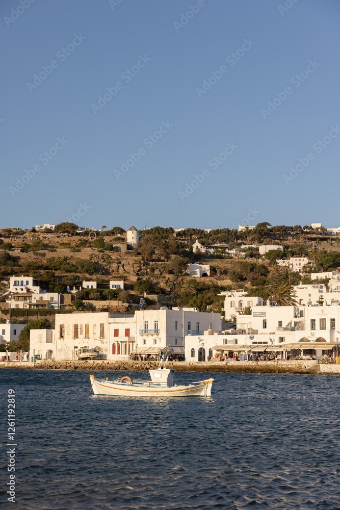View of white-washed Mykonos seafront from the water during late afternoon. View of white-washed Mykonos seafront from the water during late afternoon.