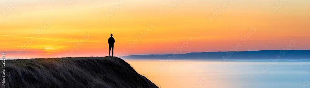 Fototapeta premium Person standing on a hilltop watching the sunset, peaceful solitude