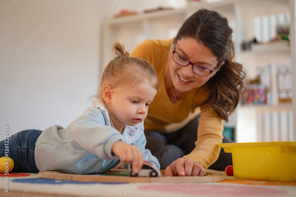 A young woman and a little girl play together on the floor with a wooden toy train, engaging in creative and educational playtime in a warm, nurturing environment A young woman and a little girl play together on the floor with a wooden toy train, engaging in creative and educational playtime in a warm, nurturing environment