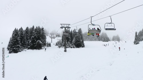 Peoples going out for skiing with chairlift in snowy winter mountain ski resort. Snow holiday concept