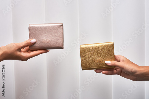 Elegant wallets in rose gold, metallic finishes, held by hands, white background, showcasing minimalist style, accessories concept