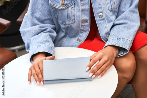Obraz na płótnie Elegant woman holding stylish blue wallet on round table, fashion accessory, casual outfit, red dress, denim jacket concept w salonie