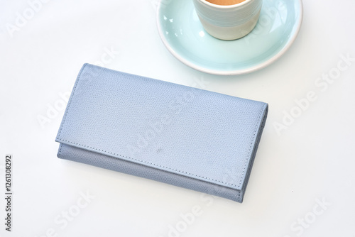 Obraz na płótnie Stylish blue wallet resting near elegant espresso cup on white background, minimalist luxury fashion concept w salonie