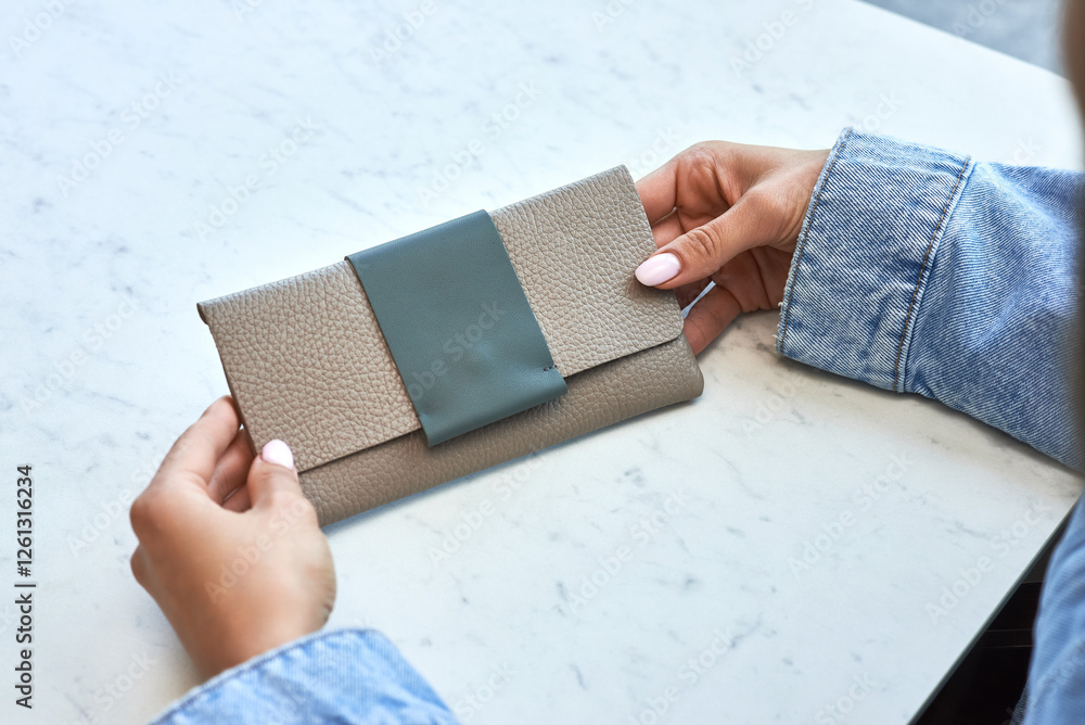 Woman holding elegant leather clutch on marble surface, modern fashion accessory for stylish women, chic design, daytime concept