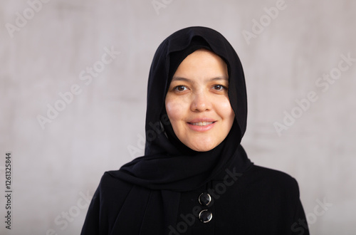Фотография Portrait of young positive woman in hijab posing on studio background