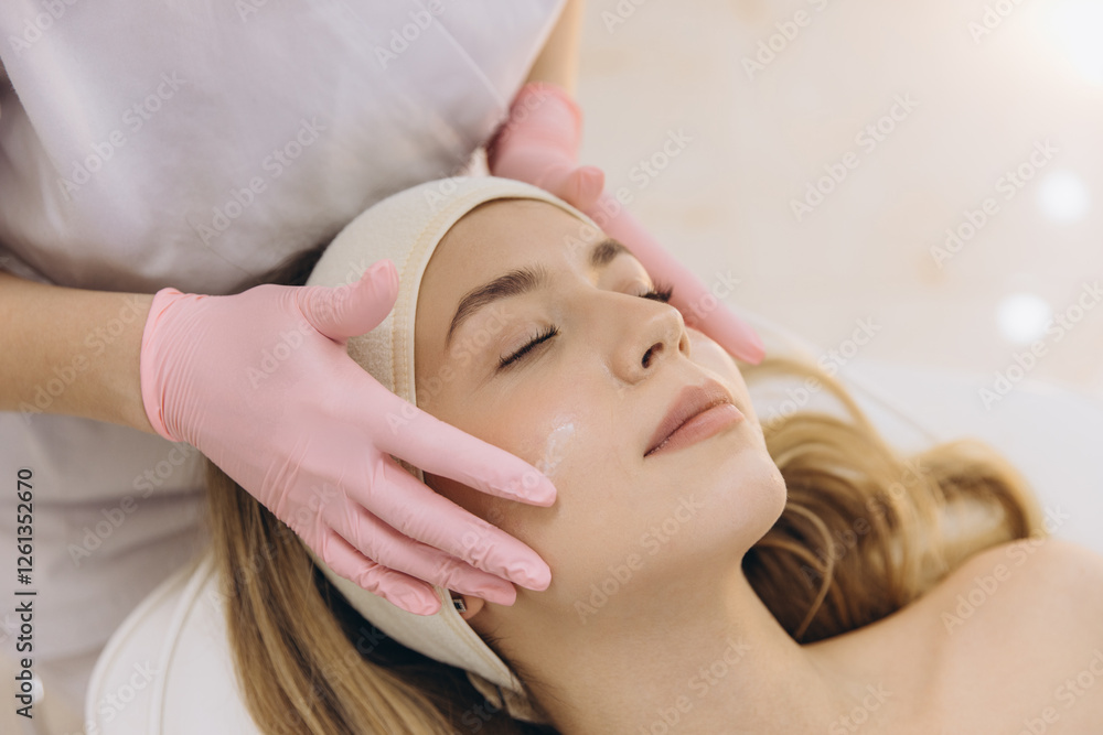 Obraz premium Skincare professional gently applying hydrating facial cream, providing nurturing treatment in tranquil spa environment