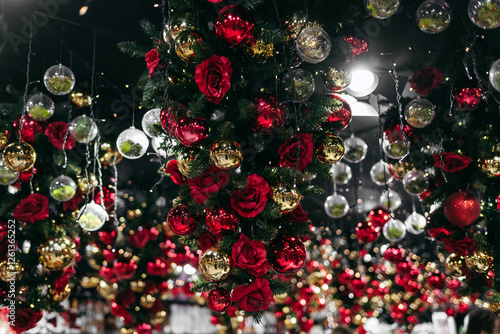 Christmas red and golden toys decorations with roses on Christmas tree, the ceiling of store. Decorations on New Year's Eve. Balls baubles hanging above ceiling inside shopping mall centre supermarket