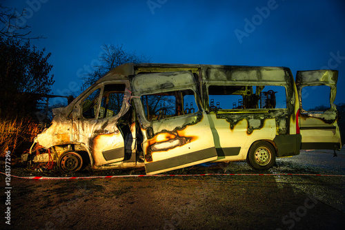 Burnt out white van at night showing fire damage photo