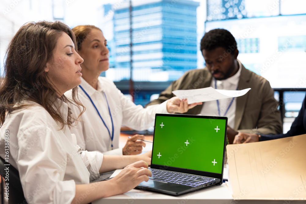 CEO uses laptop with green screen during a meeting with business associates, reviewing project development progress. Utilizing detailed analytics and mockup to ensure strategic objectives. CEO uses laptop with green screen during a meeting with business associates, reviewing project development progress. Utilizing detailed analytics and mockup to ensure strategic objectives.