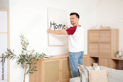 Young man hanging poster on...