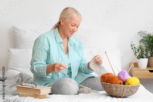 Mature woman knitting in be...