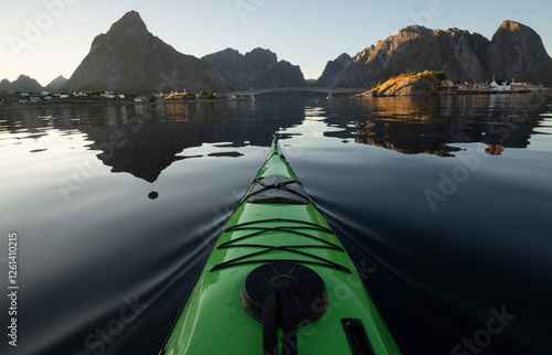 Sunset sea kayaking on a glassy ocean surrounded by mountains in Norway. 
