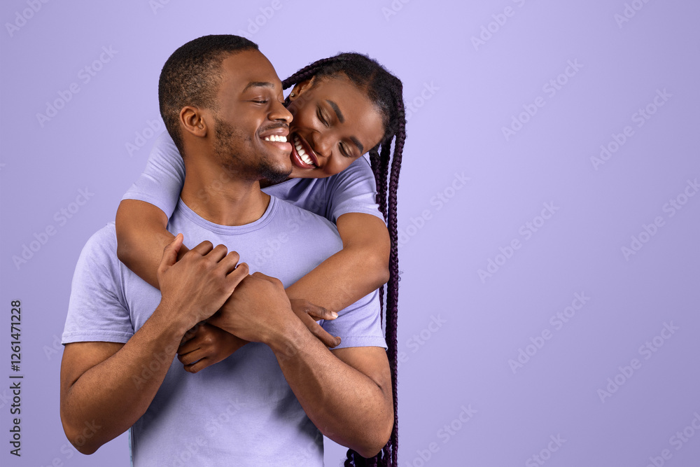 Obraz premium Happy Loving Family Concept. Front portrait of joyful black sweethearts hugging, cheerful lady embracing her man fron behind back, standing together isolated over purple violet background in studio