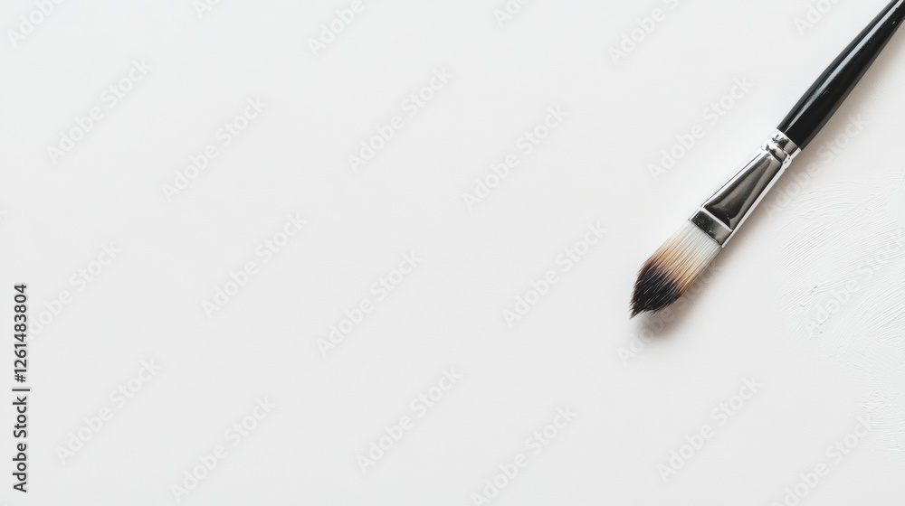 Paintbrush rests on blank canvas ready for an artist's creation in a quiet studio setting Paintbrush rests on blank canvas ready for an artist's creation in a quiet studio setting