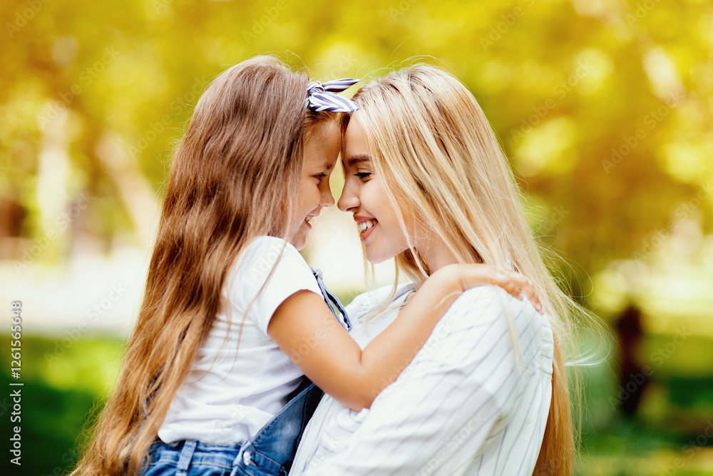 Fototapeta premium Cute Mother And Little Daughter Hugging Smiling Each Other Bonding Spending Weekend Together In Park Outside