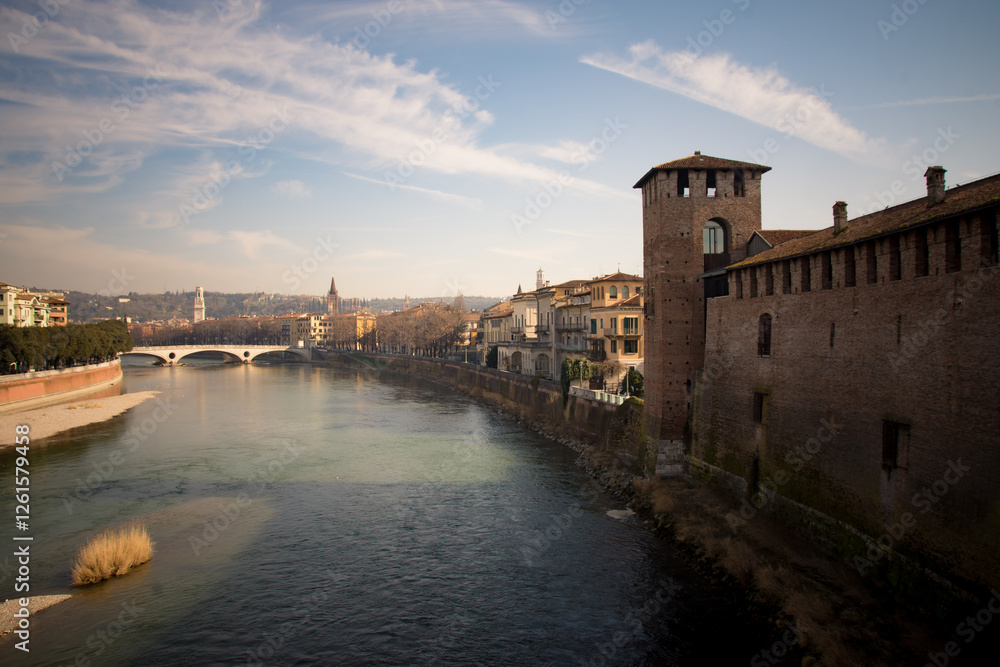 Obraz premium Adige River flowing through Verona, Italy, with historic buildings along the banks.