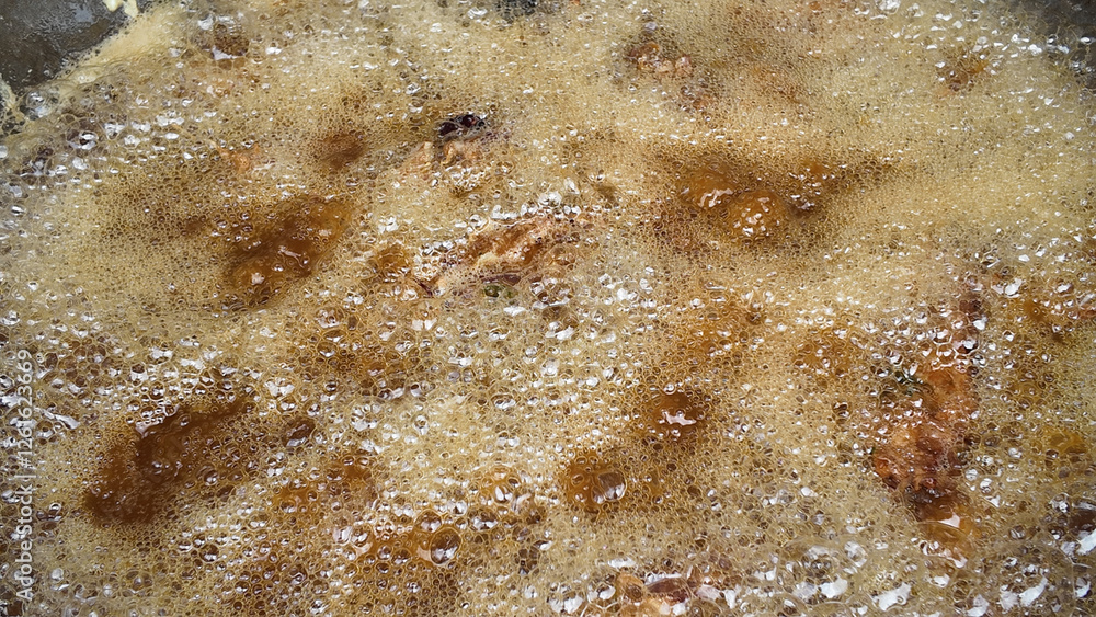 Obraz premium Cooking meat in bubbling sauce on a stovetop in a kitchen