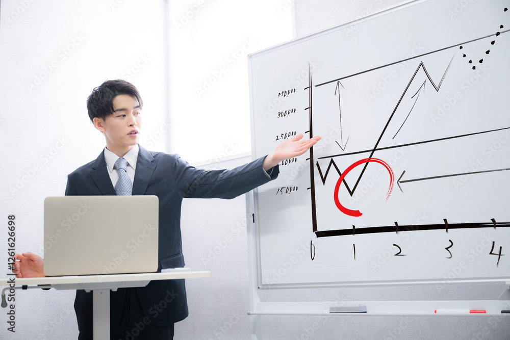 ホワイトボードを使ってマーケティングなどを説明する若い営業の男性 ホワイトボードを使ってマーケティングなどを説明する若い営業の男性