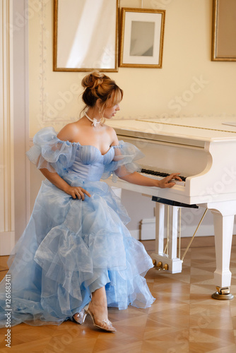 Wallpaper Mural A beautiful young woman in a flowing light blue dress plays a white piano in a luxurious interior. Historical theme concept for the cover of a book or a music album of classical music. Torontodigital.ca