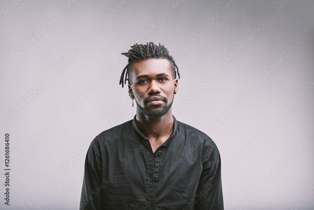 Obraz premium Serious young man with dreadlocks posing on plain background